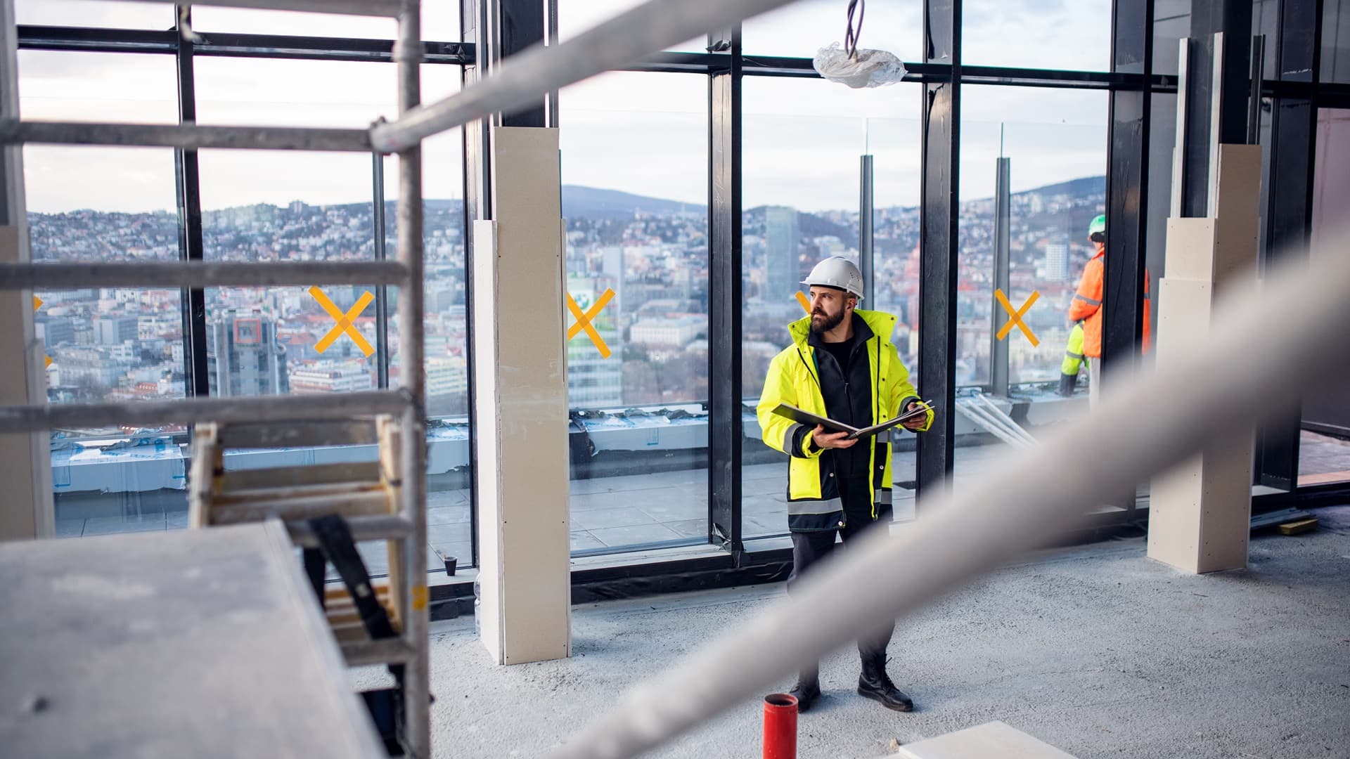 mies seisomassa rakennustyömaalla raportti kädessään