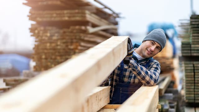 Mies tarkastelee pinossa olevaa puutavaraa.