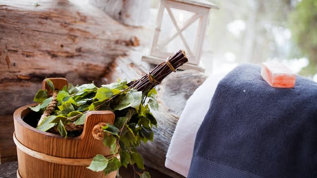 Saunatarvikkeita mökin terassilla, pyyhe, vihta ja kiulu