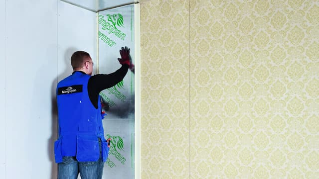 Asentaja asentaa Kingspan Therma -eristelevyä sisäseinään lisälämmöneristeeksi.