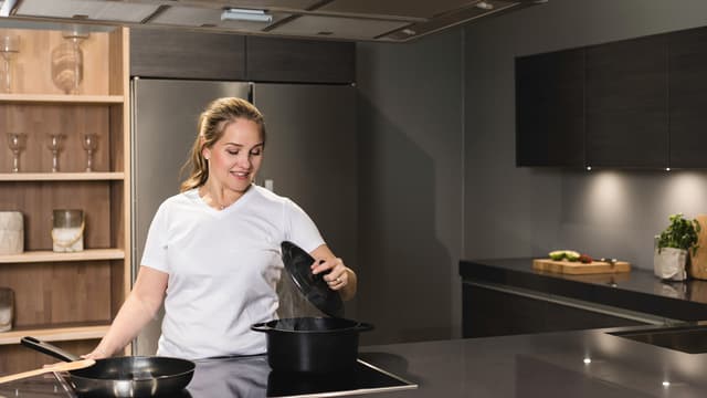 Innohome EVO nainen tekee ruokaa mustassa keittiössä