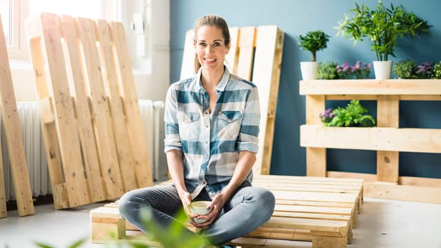 Kierrätyspuu DIY-projekti: nainen istuu kuormalavan päällä