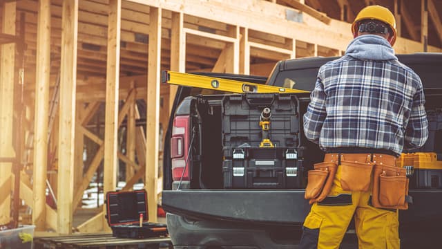 Kirvesmies työmaalla hakee tavaroitaan auton lavalta