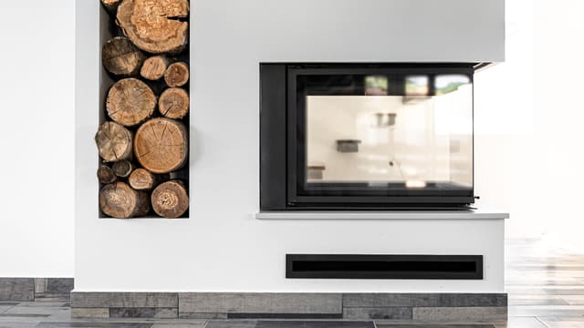 moderni valkoinen tulisija, jossa kolmella sivulla oleva luukku ja lokero polttopuille