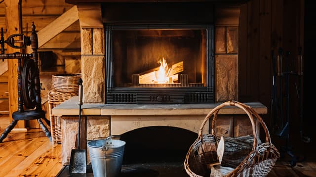 tulisija jonka edustalla halkoja ja välineet tuhkan poistamiseksi