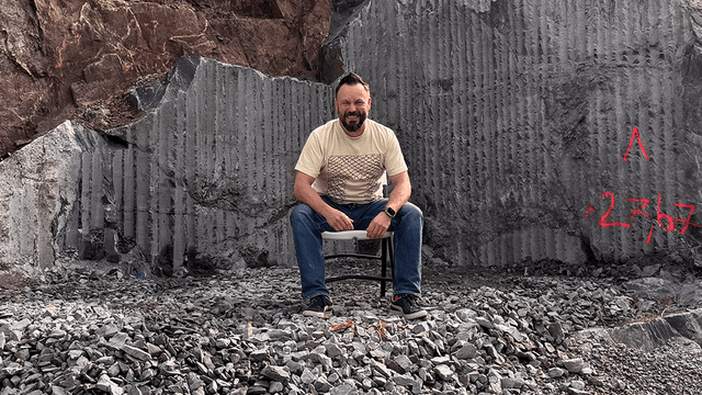 riku rantala istuu tyhjällä tontilla josta on kaivettu kalliota pois