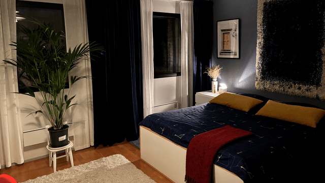 parisänky makuuhuoneessa, ryijy seinällä ja tummat verhot kiinni