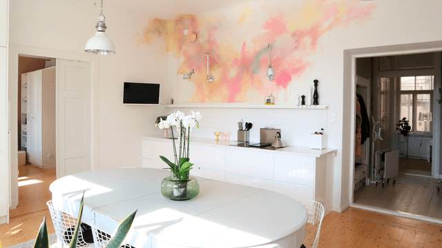 valkoinen keittiö jossa hellan tausta on maalattu pastellivärein vesiväritekniikalla